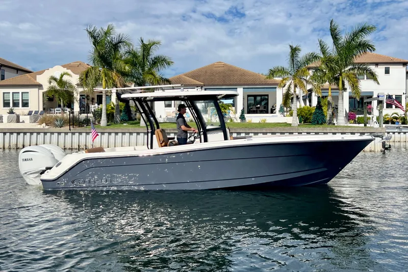 Slide: The Image of 2025 Robalo R302 Center Console boat on water, with palm trees and houses in the background. - 7