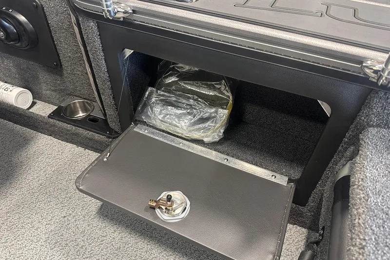 Slide: The Image of Storage compartment in 2026 Lund 1875 Pro-V boat, featuring secure latch and carpeted interior. - 29