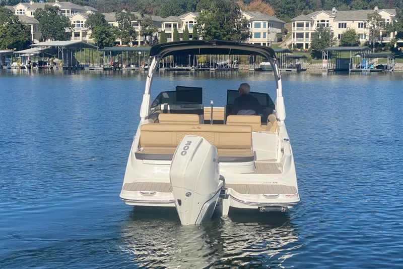 Slide: The Image of 2022 Sea Ray SDX 270 Outboard boat on a serene lake with waterfront homes. - 4