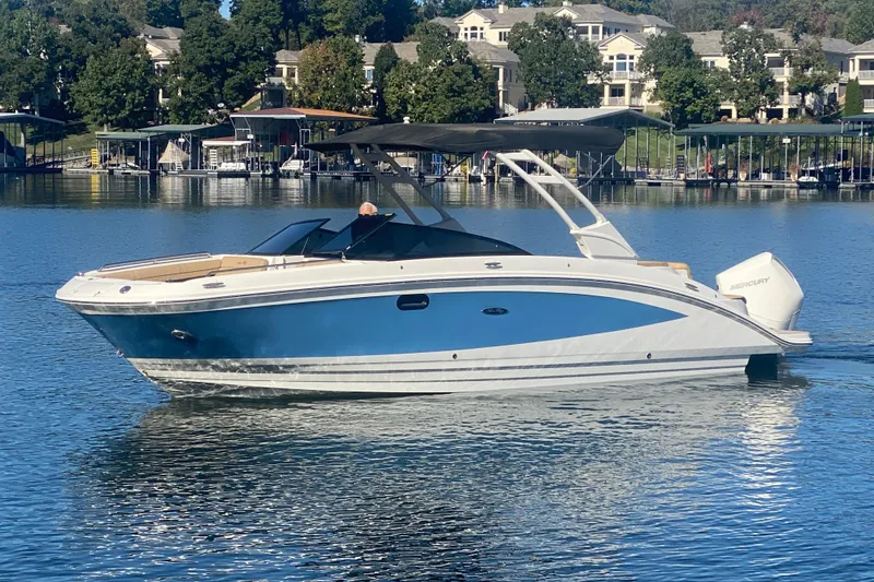 Slide: The Image of 2022 Sea Ray SDX 270 Outboard boat on a serene lake with docked boats. - 6
