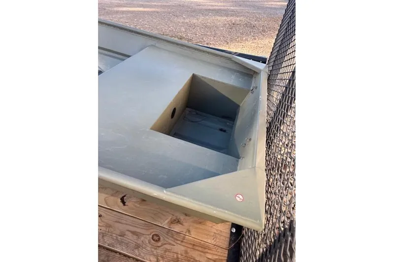 Slide: The Image of 2024 Tracker Grizzly 1436 Jon boat with motor on gravel surface. - 2