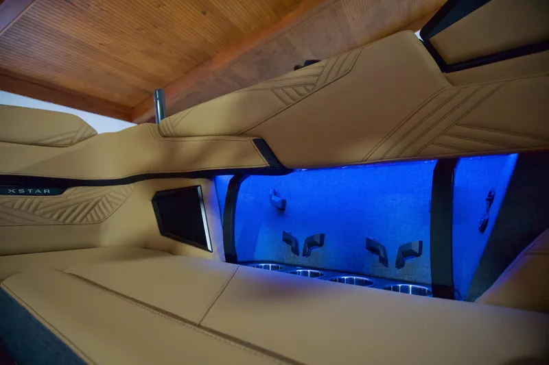 Slide: The Image of 2025 MasterCraft XStar 23 interior with tan upholstery and blue ambient lighting. - 11