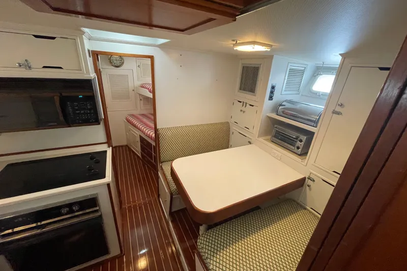 Slide: The Image of 1967 Huckins Offshore yacht interior with dining area, kitchenette, and bunk beds. - 26