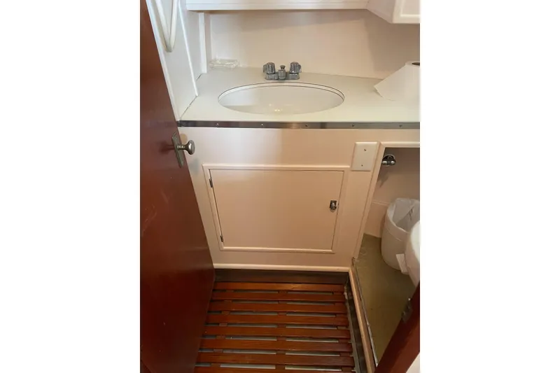 Slide: The Image of 1967 Huckins Offshore yacht bathroom with sink, wooden floor, and storage cabinet. - 31