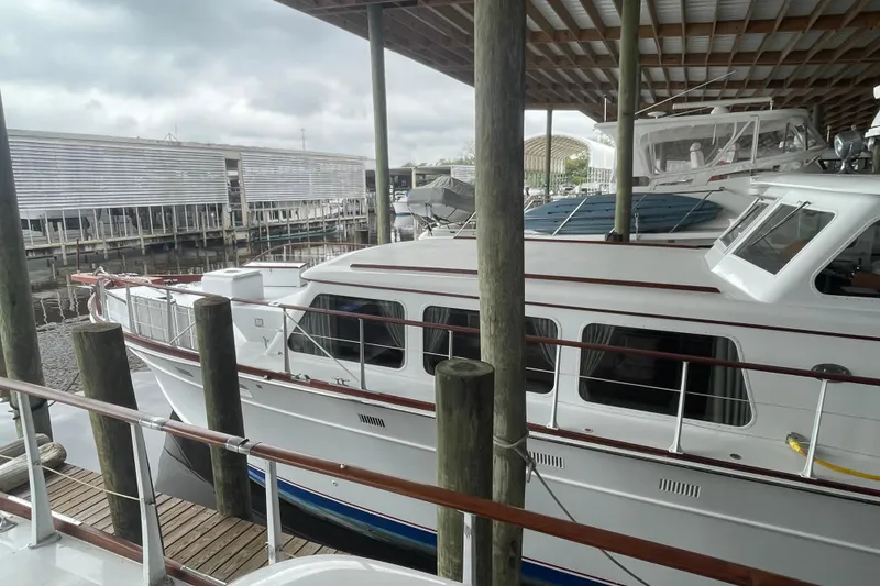 Slide: The Image of 1967 Huckins Offshore yacht docked under a covered marina with overcast skies. - 4