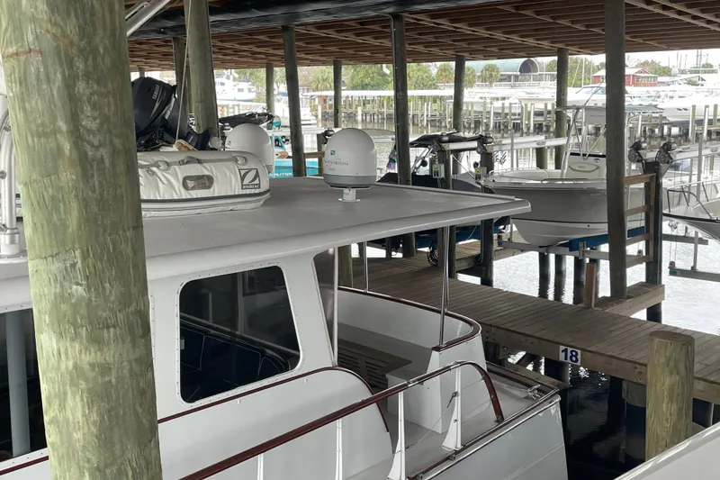 Slide: The Image of 1967 Huckins Offshore boat docked in a marina, under a wooden shelter. - 5