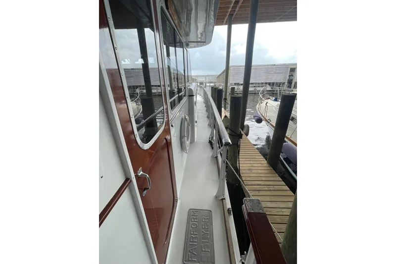 Slide: The Image of 1967 Huckins Offshore yacht docked, showcasing sleek side deck and polished wood finish. - 8