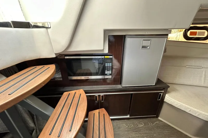 Slide: The Image of 2020 Sea Ray Sundancer 320 interior with microwave, mini-fridge, and wooden steps. - 19
