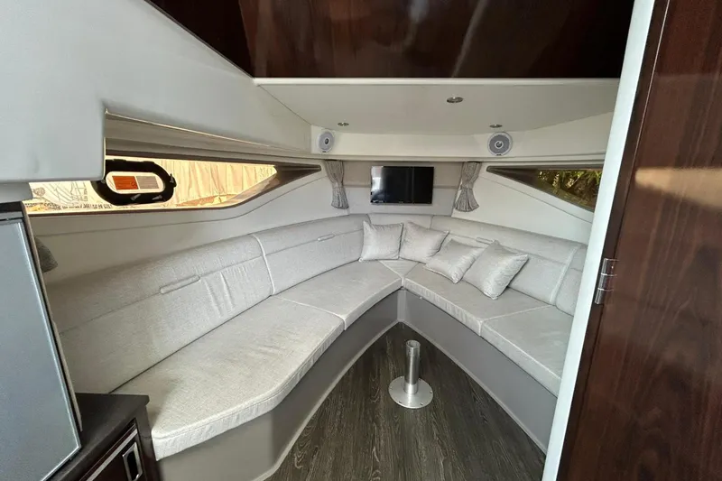 Slide: The Image of 2020 Sea Ray Sundancer 320 interior with curved seating, TV, and modern decor. - 21