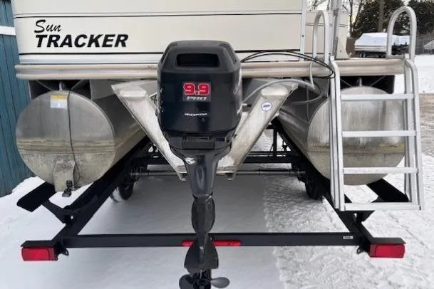 Slide: The Image of 2004 Sun Tracker Party Barge 22 Regency Edition with outboard motor and ladder in snowy setting. - 5