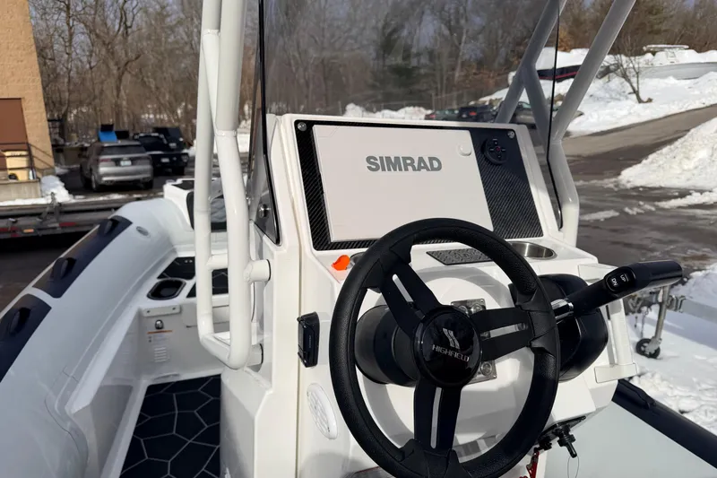 Slide: The Image of 2025 Highfield Sport 560 boat dashboard with Simrad navigation system and steering wheel. - 11