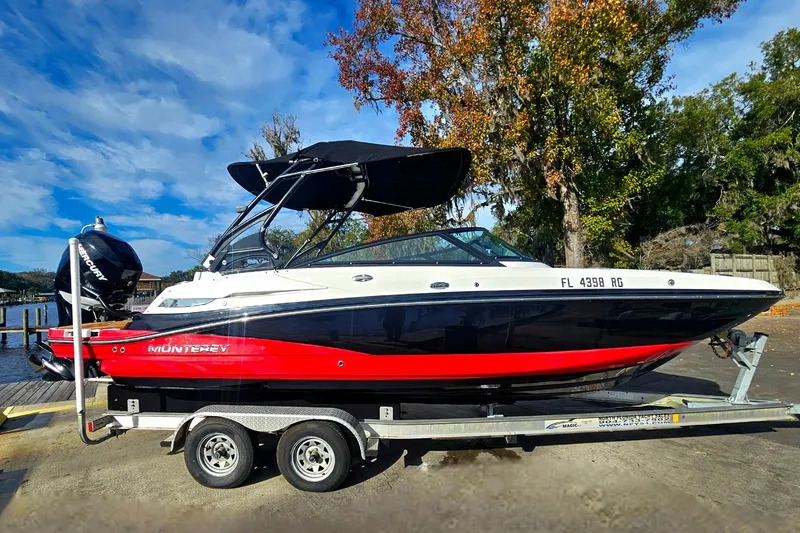 Slide: The Image of 2017 Monterey M-45 boat on trailer, vibrant red and black design, parked near trees. - 1