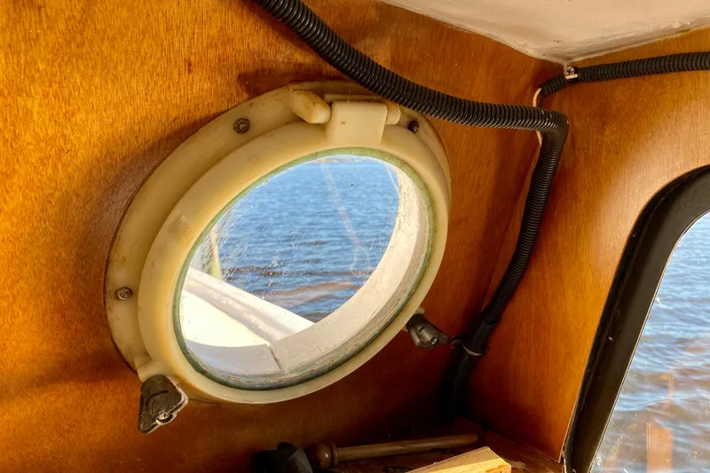 Slide: The Image of Porthole view from 1979 Outer Reef 26/31 boat, showcasing wooden interior and water outside. - 102