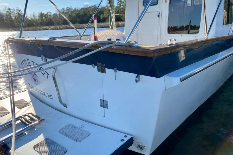 Slide: The Image of 1979 Outer Reef 26/31 boat docked on a sunny day, featuring a wooden trim. - 115