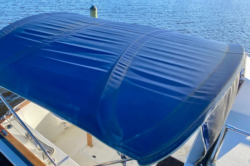 Slide: The Image of 1979 Outer Reef 26/31 boat with blue canopy on calm water. - 116