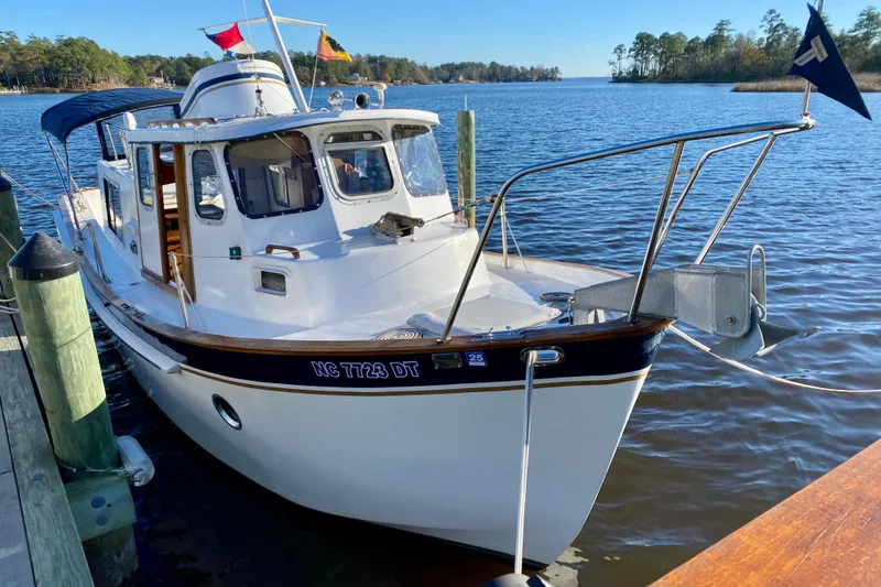 Slide: The Image of 1979 Outer Reef 26/31 boat docked on a serene lake with clear skies. - 2