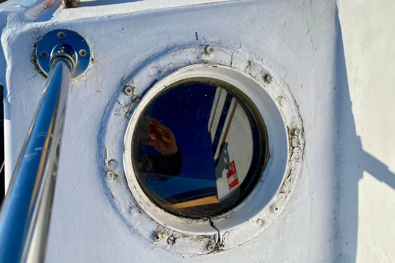 Slide: The Image of Porthole on 1979 Outer Reef 26/31 boat with reflection and metal railing. - 34