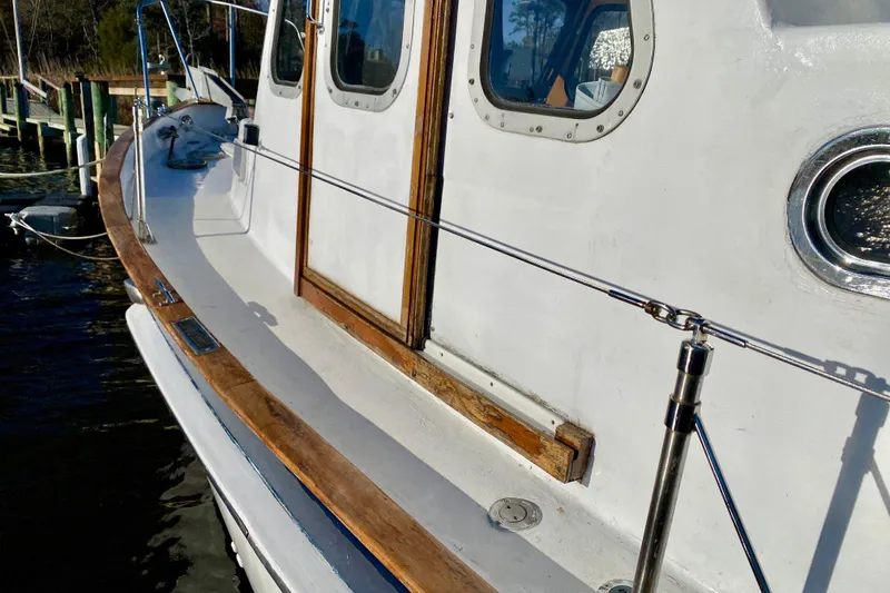 Slide: The Image of 1979 Outer Reef 26/31 boat deck with wooden trim and porthole, docked by the water. - 36