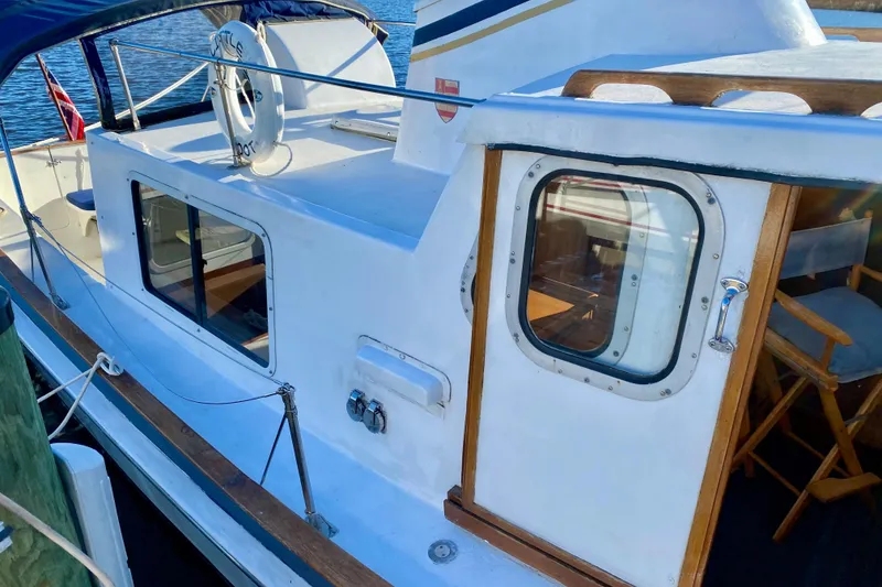 Slide: The Image of 1979 Outer Reef 26/31 boat docked, featuring a white exterior and wooden accents. - 4