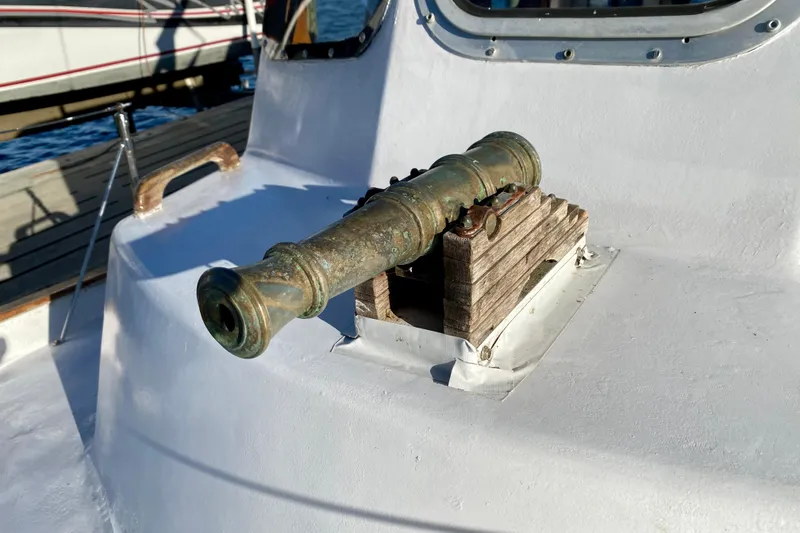 Slide: The Image of Vintage cannon mounted on 1979 Outer Reef 26/31 boat deck, docked by the water. - 46