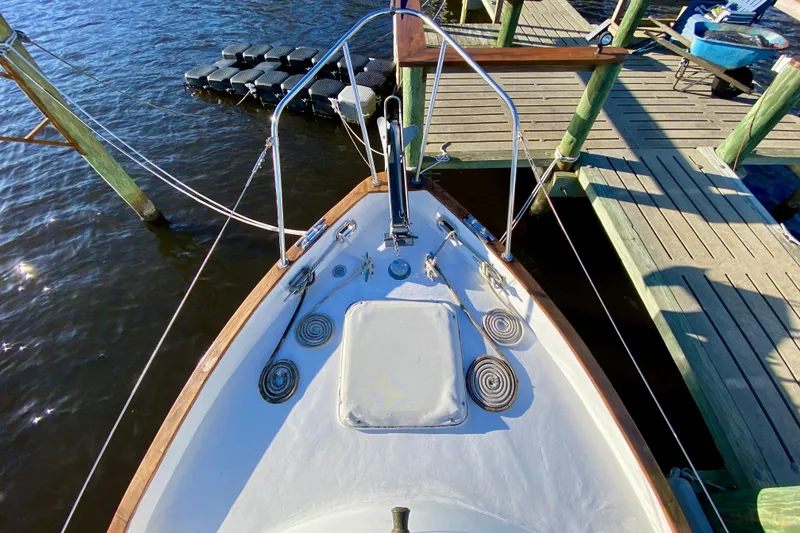 Slide: The Image of Bow view of 1979 Outer Reef 26/31 sailboat docked at a wooden pier. - 49