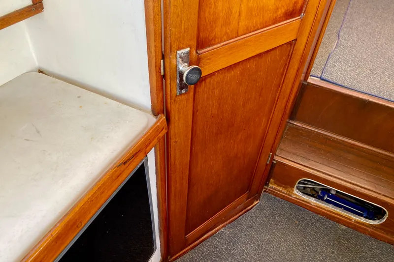 Slide: The Image of Interior of a 1979 Outer Reef 26/31 boat, featuring wooden door and bench. - 63