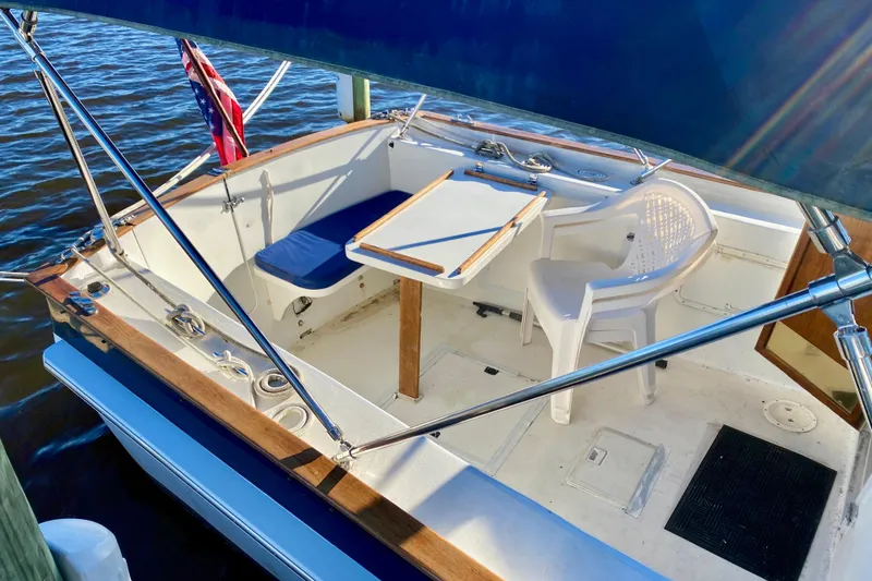 Slide: The Image of 1979 Outer Reef 26/31 sailboat cockpit with seating, table, and nautical flag. - 7