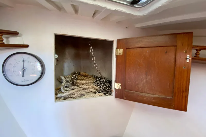 Slide: The Image of Wooden cabinet with rope and chain, next to a thermometer on a 1979 Outer Reef 26/31 boat. - 88