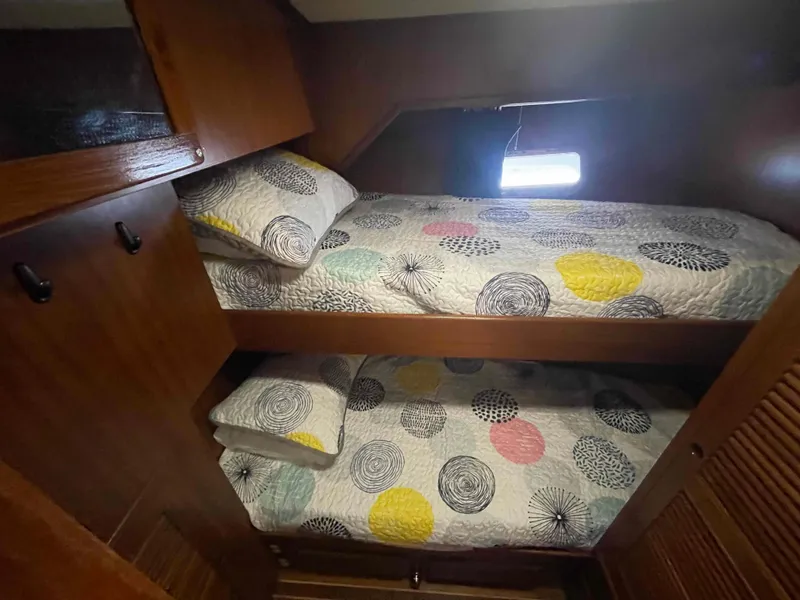 Slide: The Image of 1986 Kha Shing Spindrift yacht docked, featuring a small dinghy and clear skies. - 14