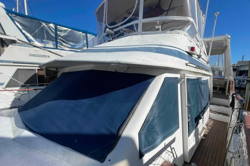 Slide: The Image of 1986 Kha Shing Spindrift yacht with blue covers, docked under clear sky. - 54