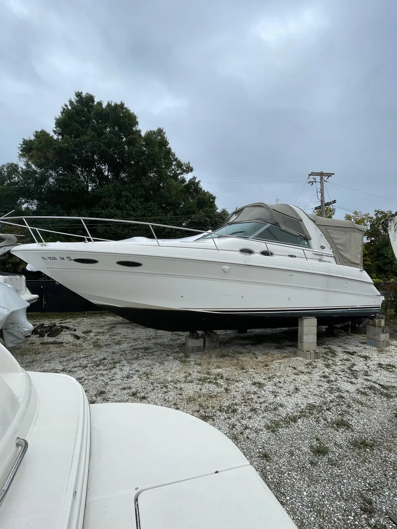 The Image of 2001 Sea Ray 310 Sundancer boat on land, overcast sky, trees in background. - 1