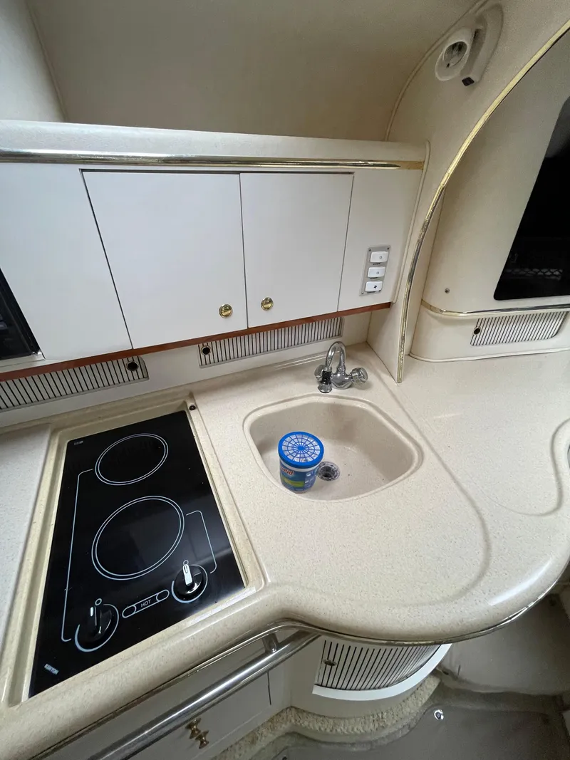 Slide: The Image of 2001 Sea Ray 310 Sundancer kitchen with stove, sink, and storage cabinets. - 27