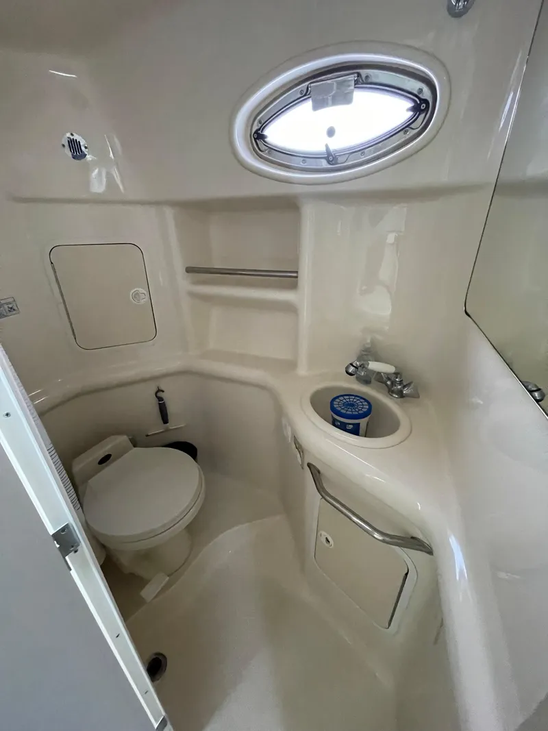 Slide: The Image of 2001 Sea Ray 310 Sundancer bathroom with toilet, sink, and porthole window. - 32