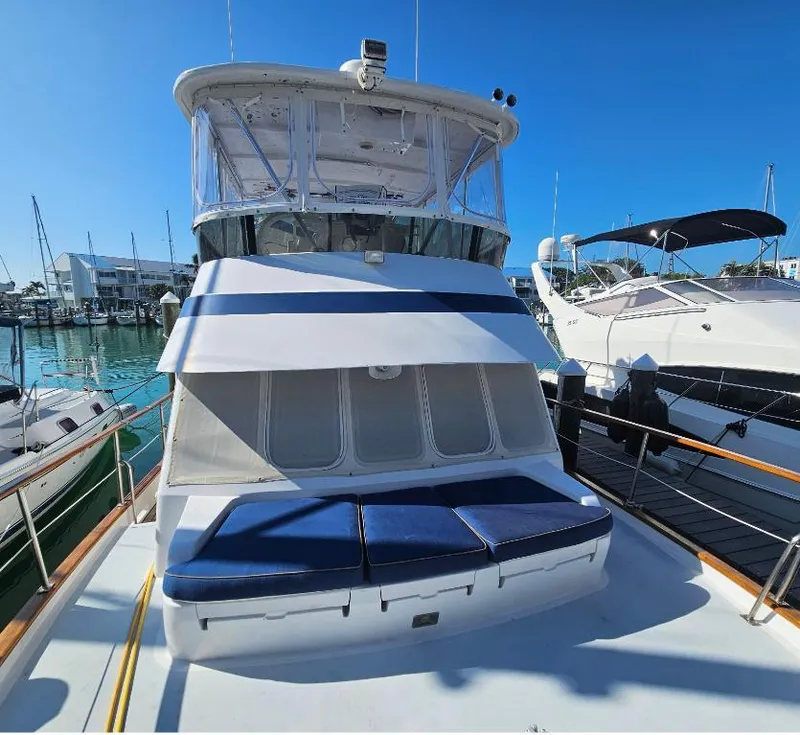 Slide: The Image of 1987 Tayana 45 Expedition Trawler docked, featuring blue cushions and a clear sky backdrop. - 5