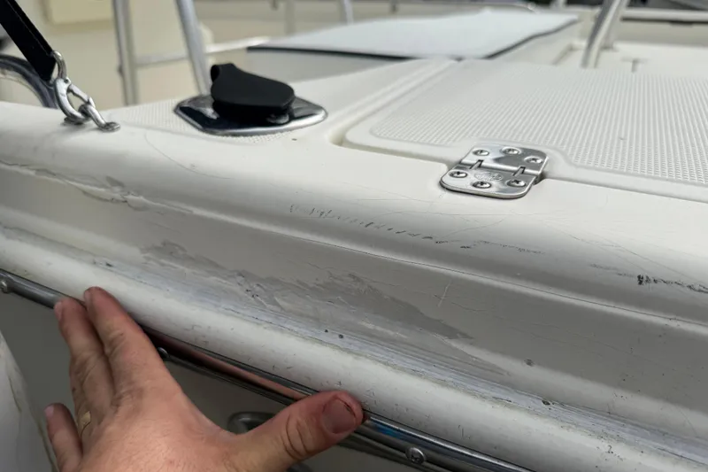 Slide: The Image of 2003 Scout 240 Bay Scout boat with visible hull damage and hand inspection. - 18