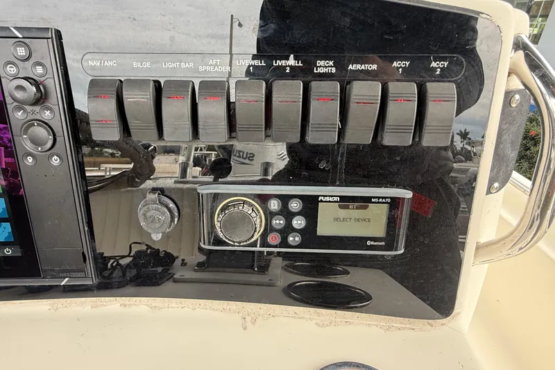 Slide: The Image of Control panel of a 2003 Scout 240 Bay Scout boat with switches and a Fusion stereo. - 33