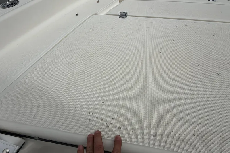 Slide: The Image of 2003 Scout 240 Bay Scout boat deck with textured surface and hand visible. - 42