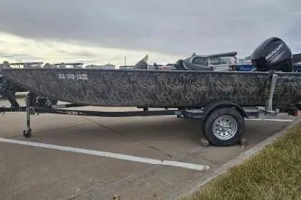 Slide: The Image of 2016 Lowe Stinger 175 boat on trailer in parking lot, camo design, overcast sky. - 2
