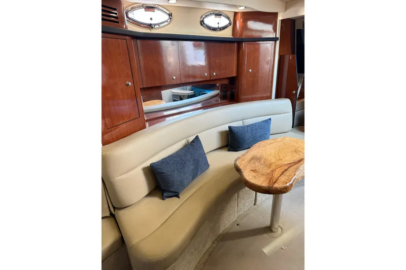 Slide: The Image of 2006 Sea Ray 340 Sundancer interior with curved seating, wooden table, and blue cushions. - 32