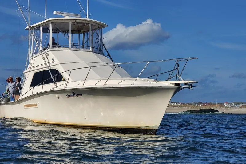 Slide: The Image of 1991 Pacemaker 37 Sportfisherman boat on water, clear sky, people onboard. - 2