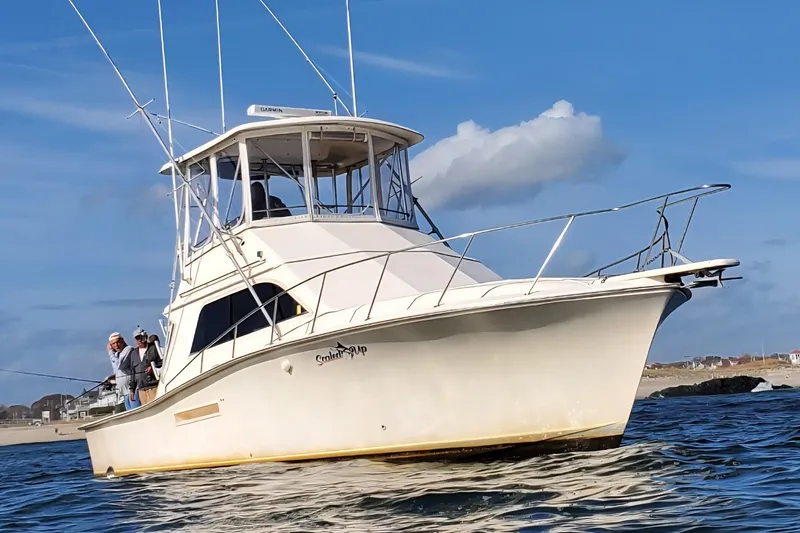 Slide: The Image of 1991 Pacemaker 37 Sportfisherman boat on water, with people fishing, under clear blue sky. - 3
