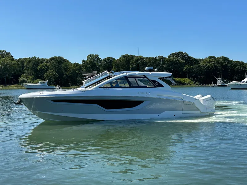 Slide: The Image of 2026 Cruisers Yachts 42 GLS OB on serene water with houses in the background. - 5