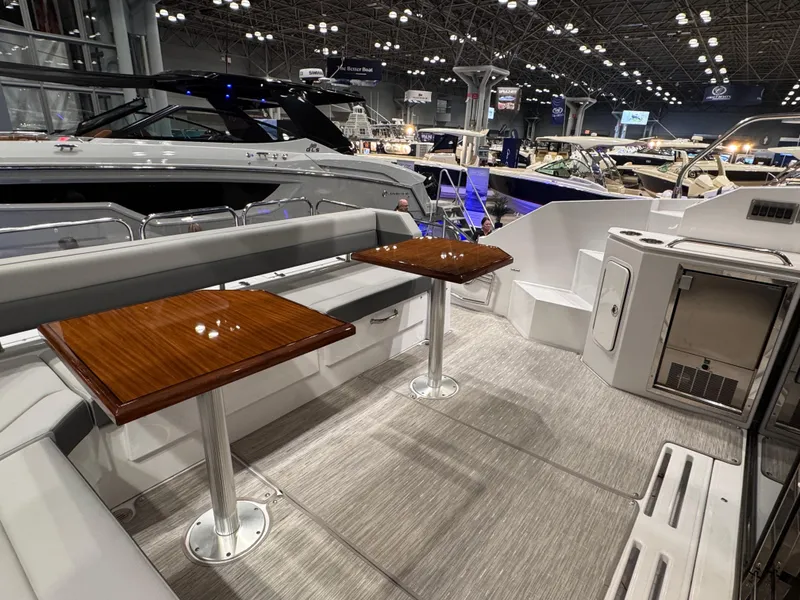 Slide: The Image of 2024 Cruisers Yachts 42 Cantius interior with sleek seating and wooden tables at a boat show. - 5