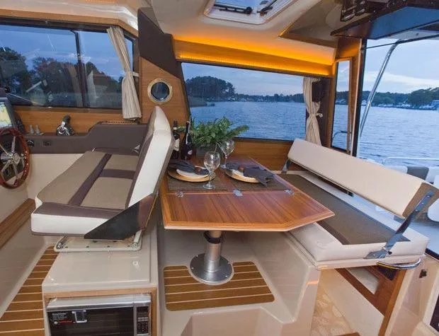 Slide: The Image of Manufacturer Provided Image: Interior of 2025 Ranger Tugs R-29 S with dining area and scenic window view. - 11