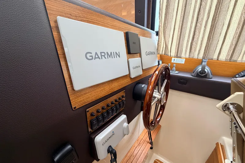 Slide: The Image of 2025 Ranger Tugs R-29 S helm with Garmin navigation system and wooden steering wheel. - 12