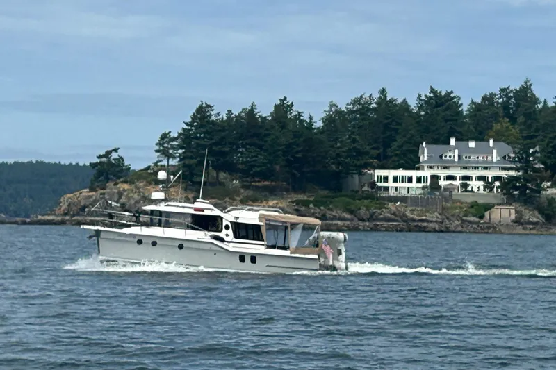 Slide: The Image of 2025 Ranger Tugs R-29 S cruising near a scenic coastal estate. - 4