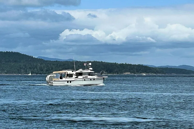 Slide: The Image of 2025 Ranger Tugs R-29 S cruising on a scenic lake with forested hills. - 5