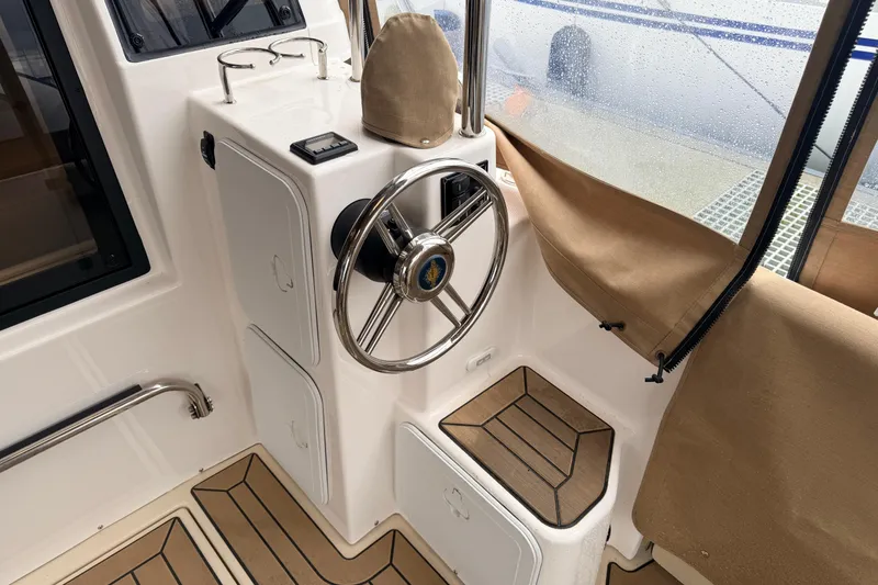 Slide: The Image of 2025 Ranger Tugs R-29 S helm with steering wheel and beige interior accents. - 8