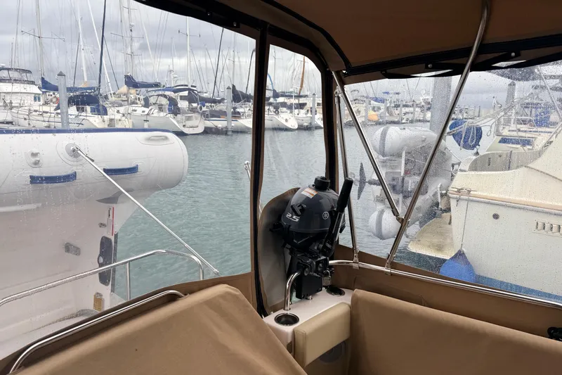 Slide: The Image of 2025 Ranger Tugs R-29 S interior view with marina backdrop and outboard motor. - 9