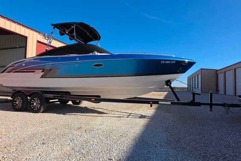 Slide: The Image of 2021 Formula 270 Bowrider boat on trailer, parked outdoors under clear blue sky. - 2